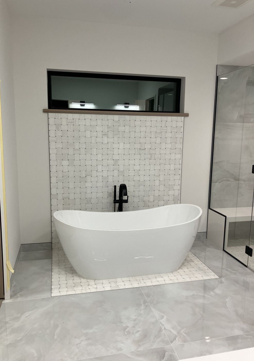 Freestanding tub on a basketweave marble mosaic with a matching wall