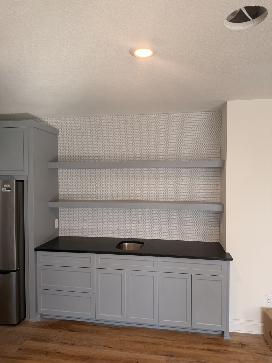 Kitchenette with a white mosaic tile wall and floating shelves