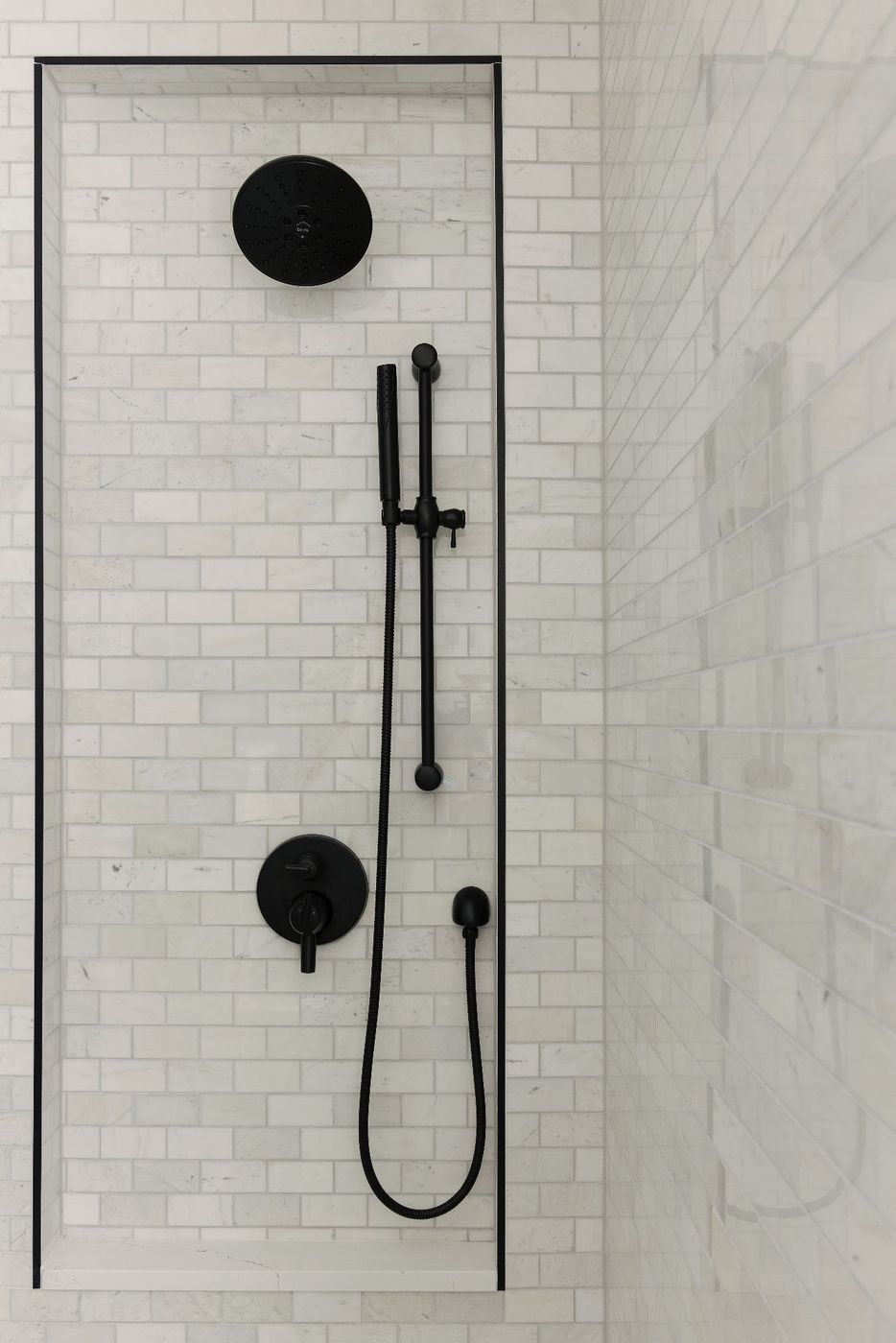 Marble subway tile shower wall framed with black trim