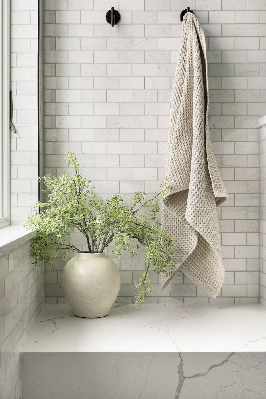 White subway tile shower with a marble bench