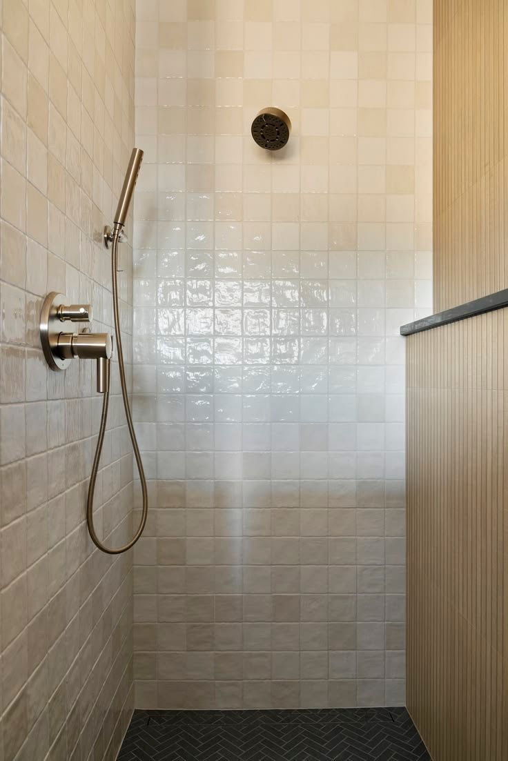 Shower with cream glossy square tile and a dark herringbone floor