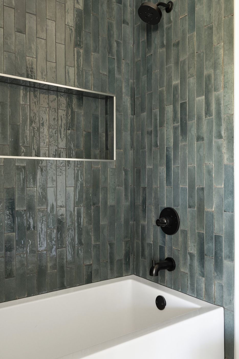Tub surround in glossy green vertical tile with a long niche